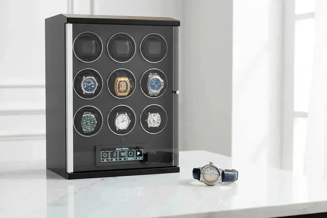 Black watch winder displaying nine automatic watches, with one watch on a white marble surface.