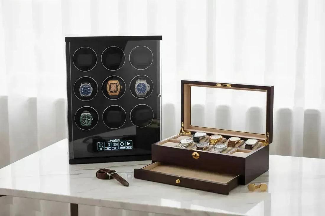 Black multi-watch winder with luxury watches next to a wooden watch box on a marble surface.