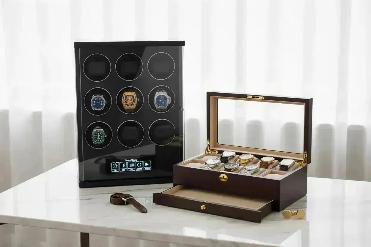 Black multi-watch winder with luxury watches next to a wooden watch box on a marble surface.