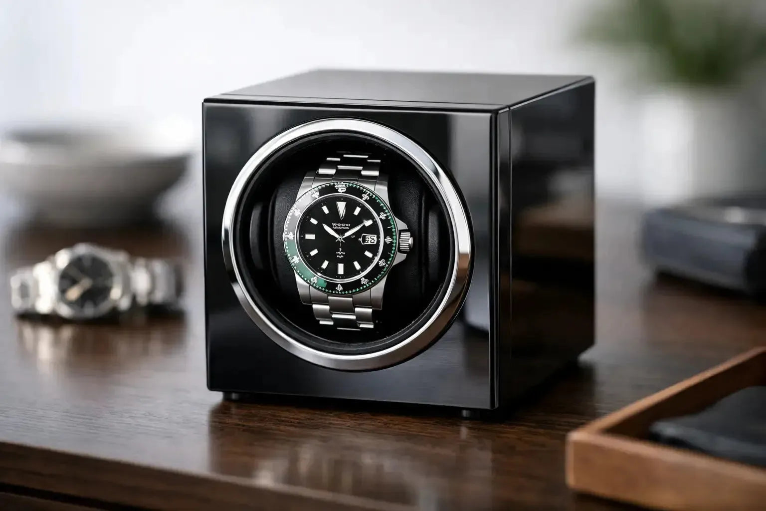 A sleek, black glossy single watch winder holding a stainless steel Rolex watch on a wooden desk.