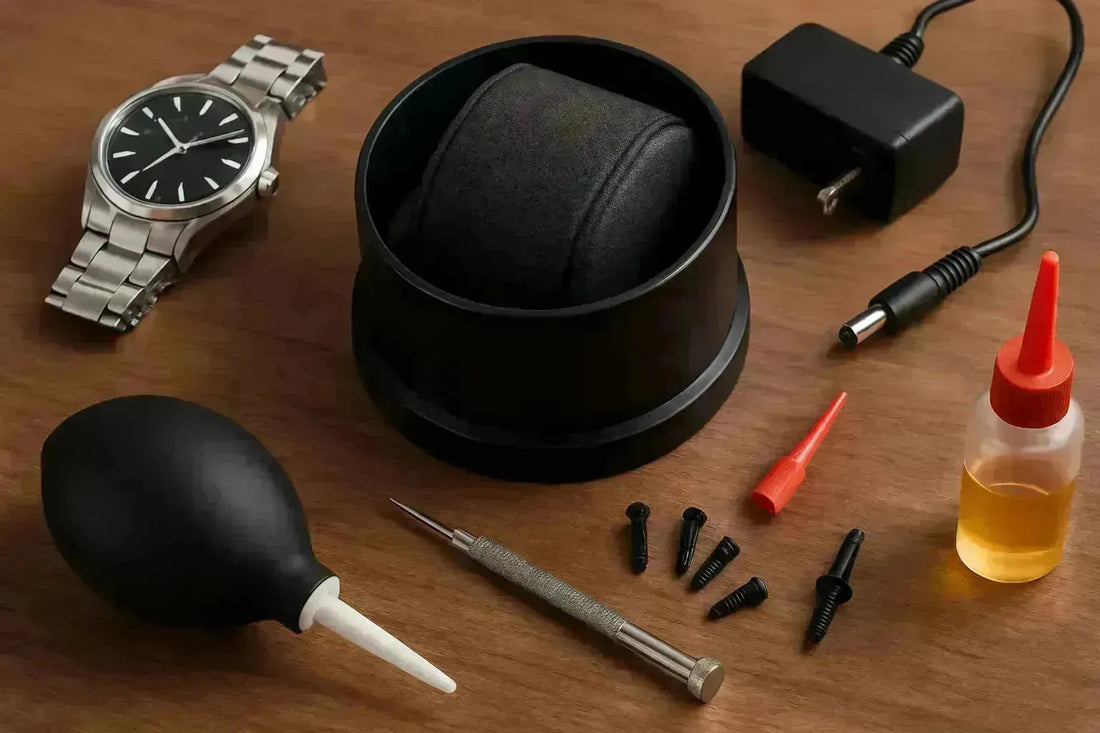 Watch winder maintenance parts: black winder, power adapter, tools, oil, and a silver watch on wood.