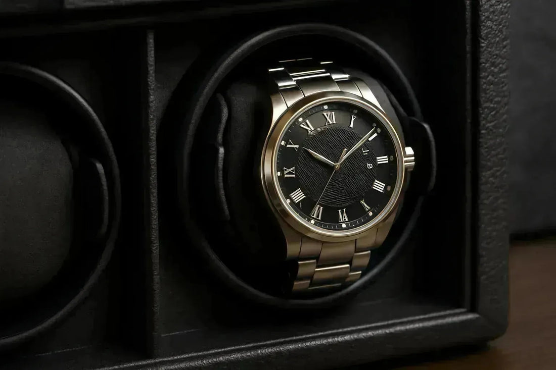 Gold and black automatic watch with Roman numerals in a luxurious black leather watch winder.