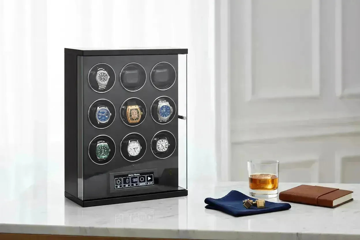 Black watch winder with nine luxury watches, a glass of whiskey, and cufflinks on a marble table.