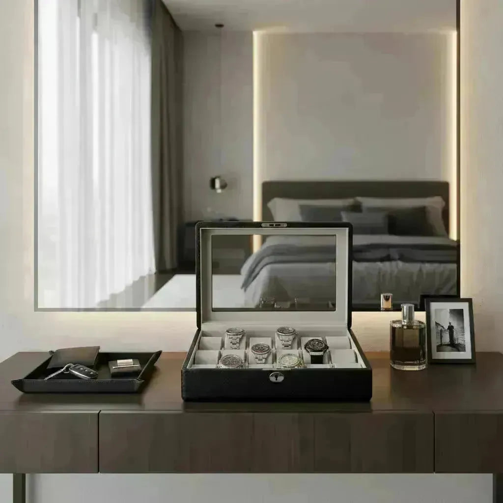 Black Tempus watch box with glass lid displaying six watches on a modern vanity.