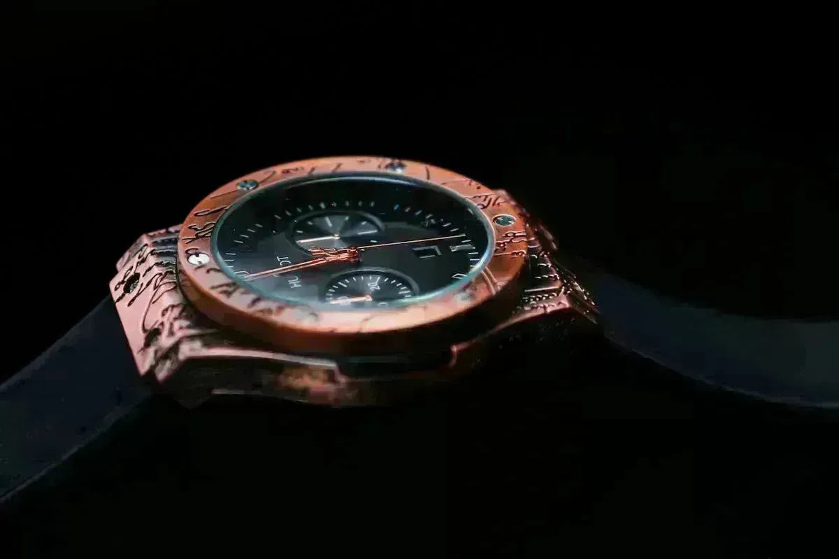 Luxury Hublot watch with a copper-toned engraved bezel and black dial on a black strap against a dark background.
