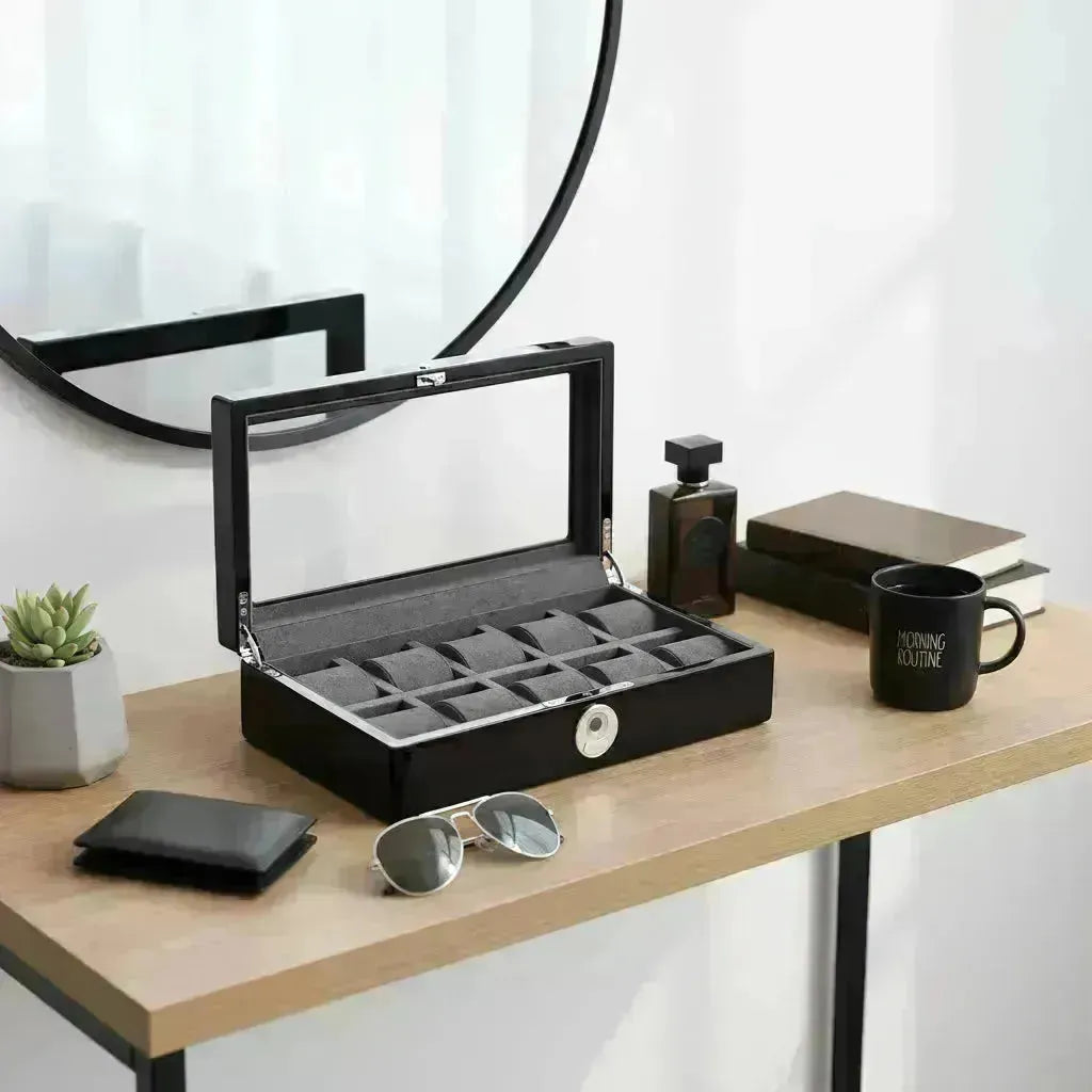 Sleek black watch box with a glass lid and grey velvet interior, ideal for storing luxury timepieces.