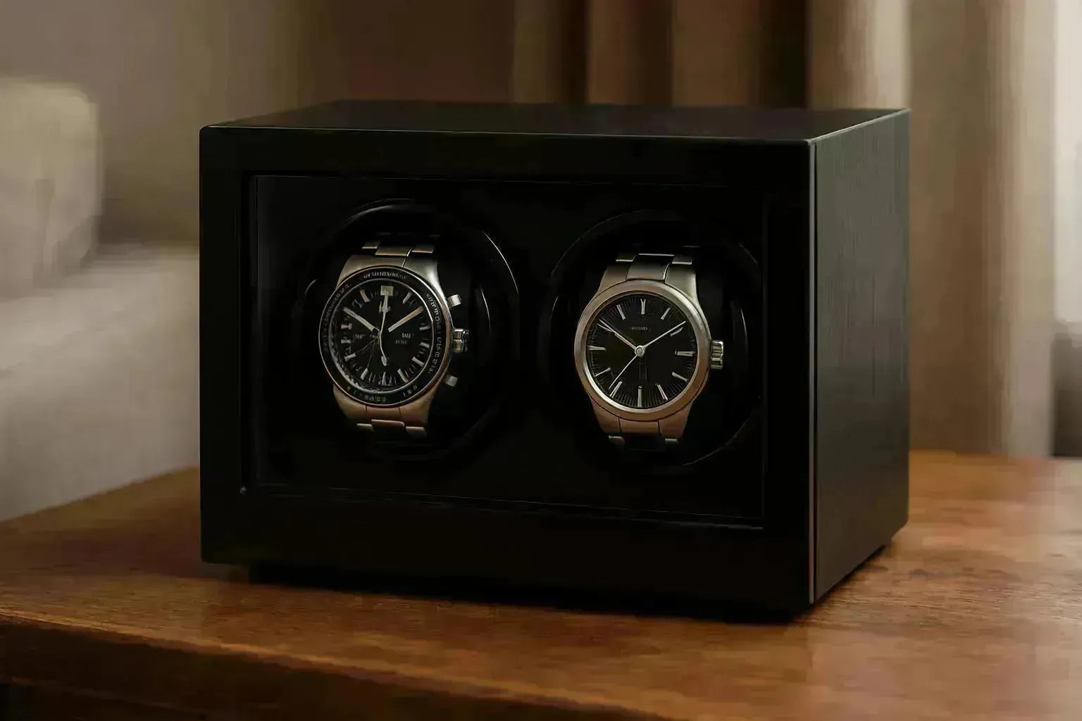 Two luxury watches displayed in a sleek, black wooden double watch winder on a polished table.