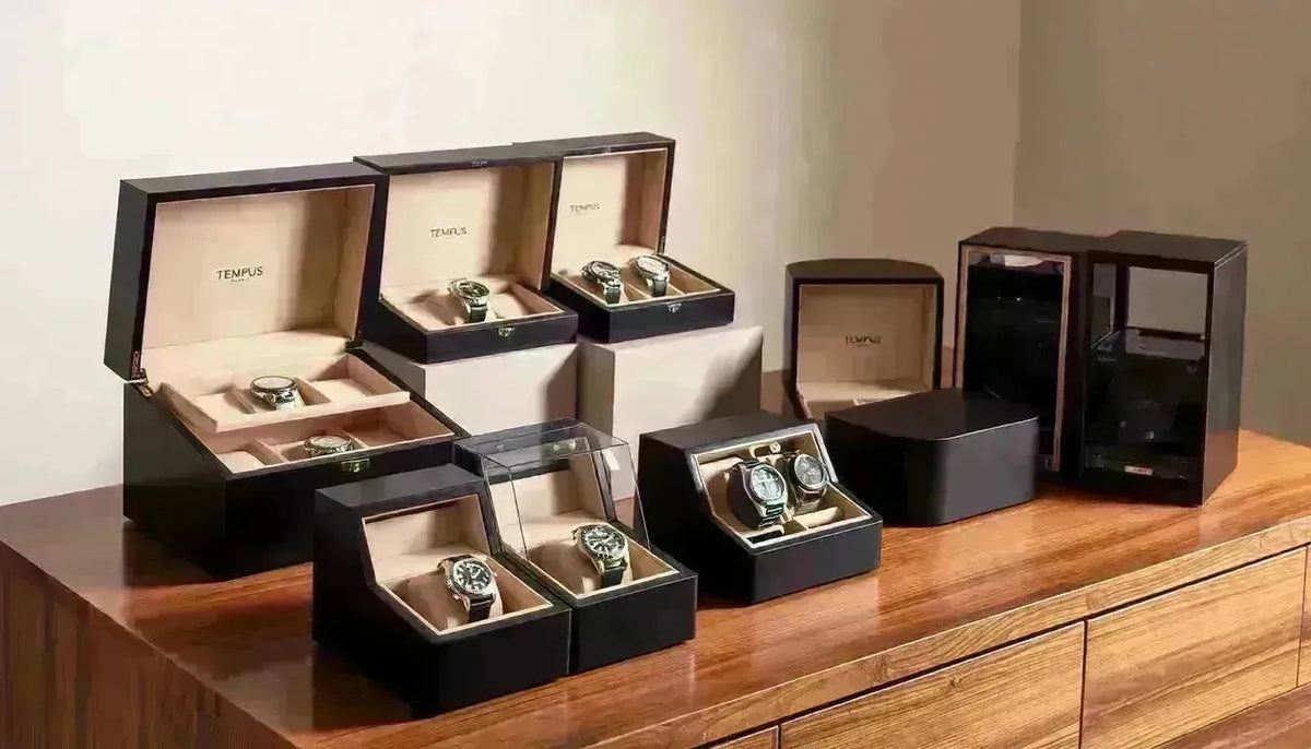Luxury black wooden watch display cases and winders holding premium timepieces on a wooden surface.