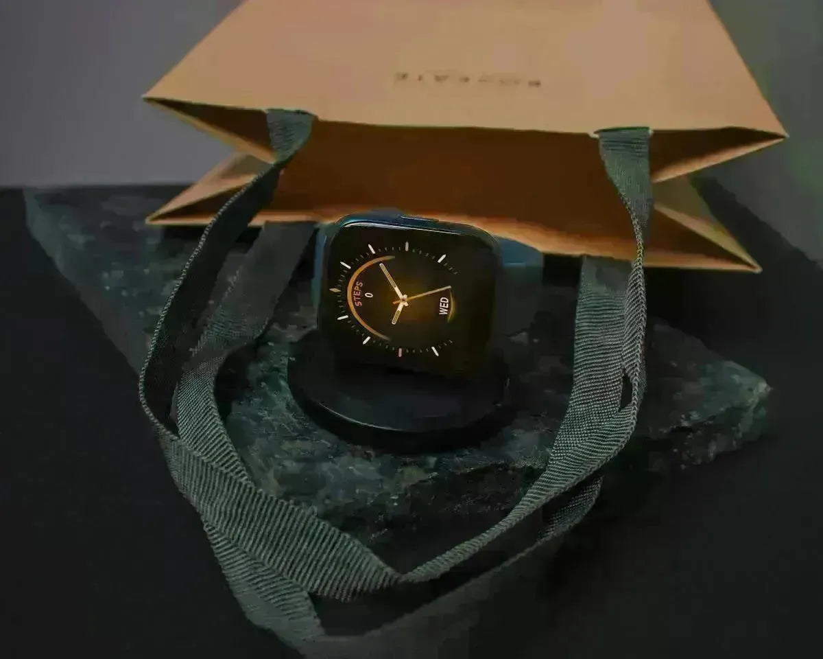Smartwatch resting on a circular charging dock atop a textured stone base near a paper gift bag.
