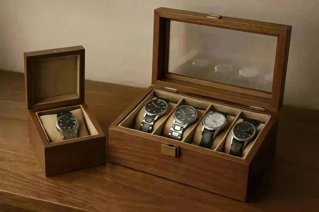 Wooden watch box with a glass lid storing four watches, next to a single watch box.