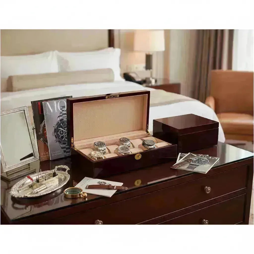 Open dark wood watch case with four luxury watches on a dresser in a bedroom.
