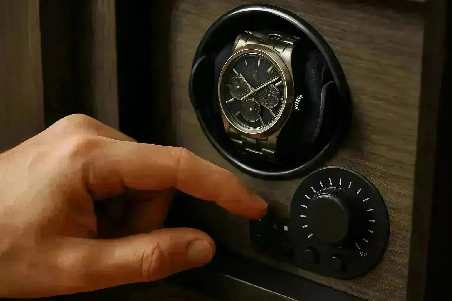 Hand adjusting the TPD settings on a wooden watch winder with a luxury chronograph watch inside.