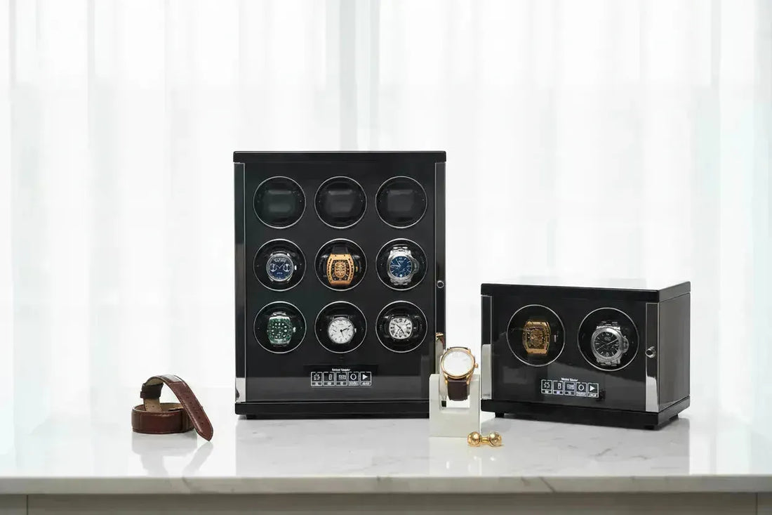 Two black watch winders, one large with nine watches and one small with two, on a white surface.