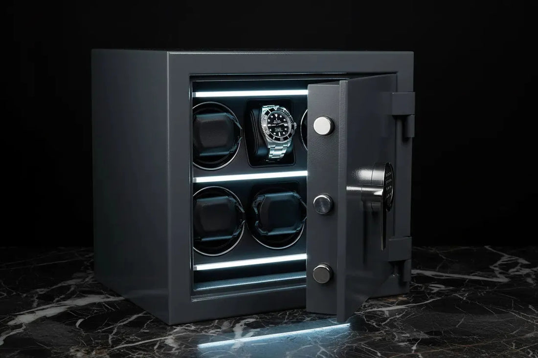 Open dark gray watch winder safe with a silver Rolex and four empty winder slots, illuminated by cool white light.