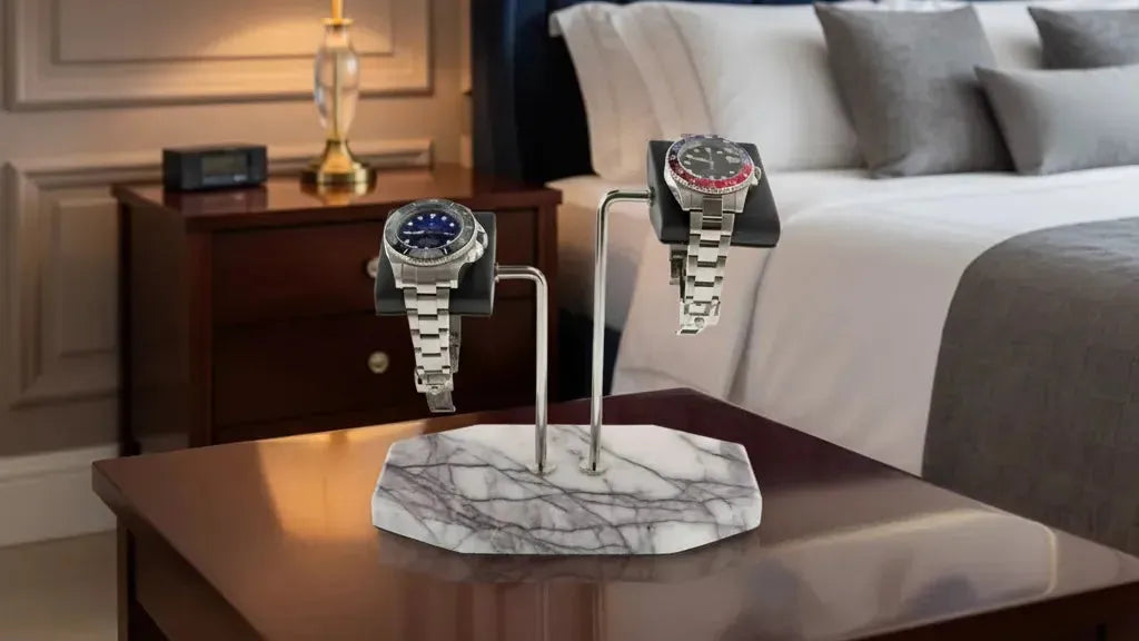 Luxury marble watch stands displaying two elegant timepieces in a sophisticated bedroom setting.