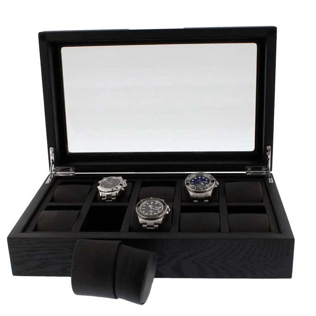 The 10 Watch Box Premium Black Oak Veneer by Tempus Luxury displays three silver wristwatches inside its glass lid, with several empty compartments and a black watch cushion from Tempus Luxury Watch Winders set outside the box.