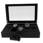 The 10 Watch Box Premium Black Oak Veneer by Tempus Luxury displays three silver wristwatches inside its glass lid, with several empty compartments and a black watch cushion from Tempus Luxury Watch Winders set outside the box.