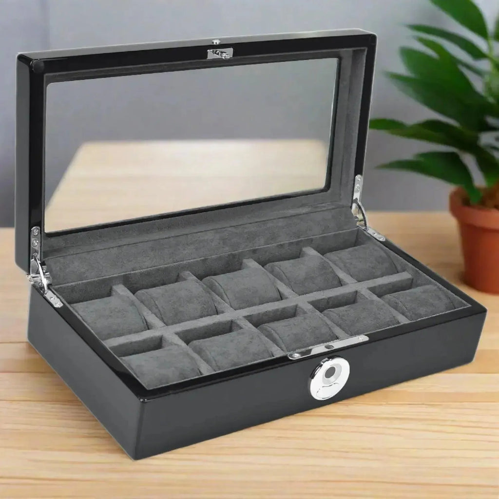 The Tempus Luxury Watch Winders 10 Watch Box in Black Piano Finish with a biometric lock and glass lid is open on a wooden table, with a green potted plant in the background.