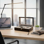 Open piano black gloss 12-watch box with grey lining and glass lid, displaying watches on a desk.
