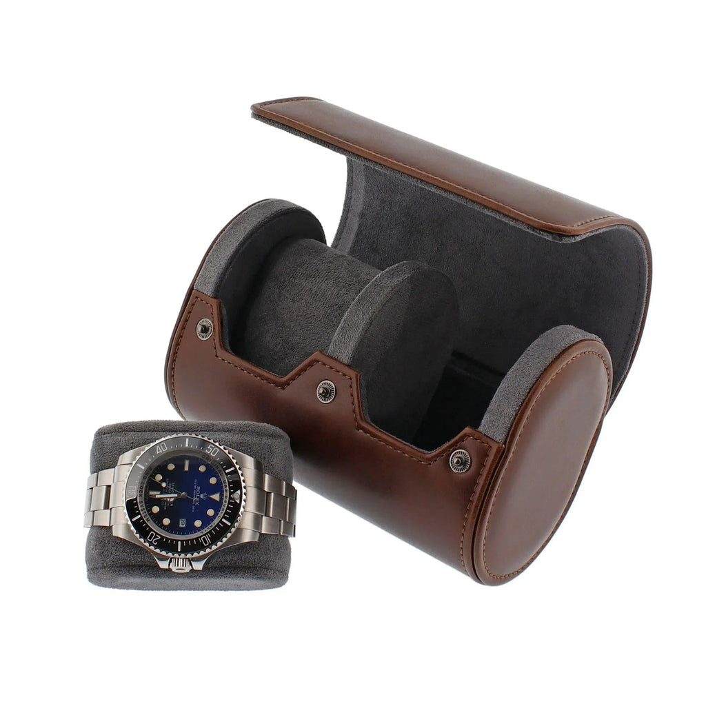Vintage brown leather 2-watch roll with grey suede lining, open next to a watch on a matching cushion.