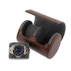 Vintage brown leather 2-watch roll with grey suede lining, open next to a watch on a matching cushion.