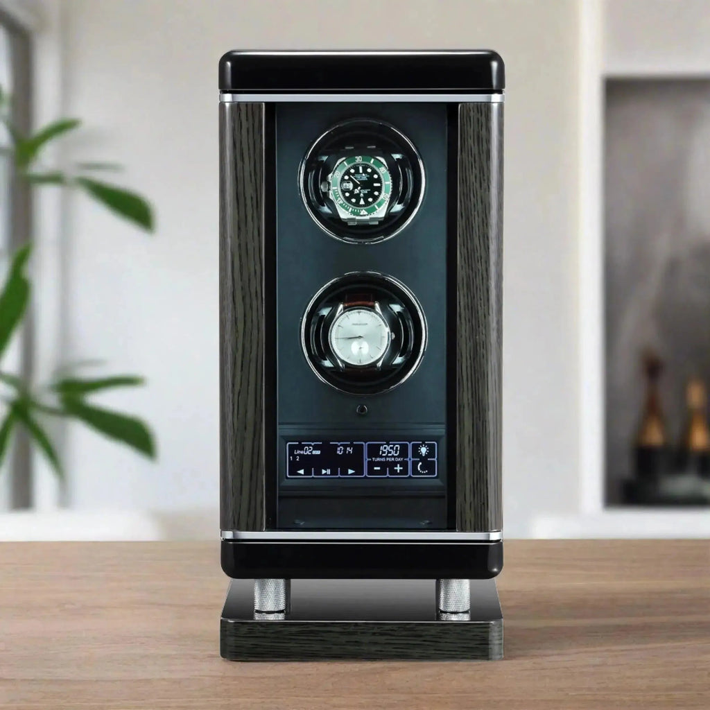 The Tempus Luxury Watch Winders 2 Watch Winder for Automatic Watches For Men with BioMetric Access Technology features a black and silver design, digital controls, and holds two watches, displayed on a wooden surface with plants and shelves in the blurred background.