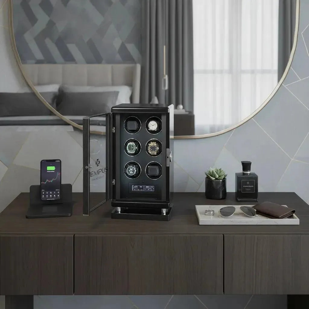 A modern wooden dresser holds a phone on a stand, the Tempus Luxury Watch Winder 6 with BioMetric Technology by Tempus for automatic watches, a small plant, cologne bottle, sunglasses, and wallet. A round mirror and bed are in the background.