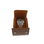 An Aevitas Premium Single Watch Roll in brown leather with super soft tan suede lining holds a silver wristwatch with black dial, displayed upright against a white background, with snap buttons on the front.