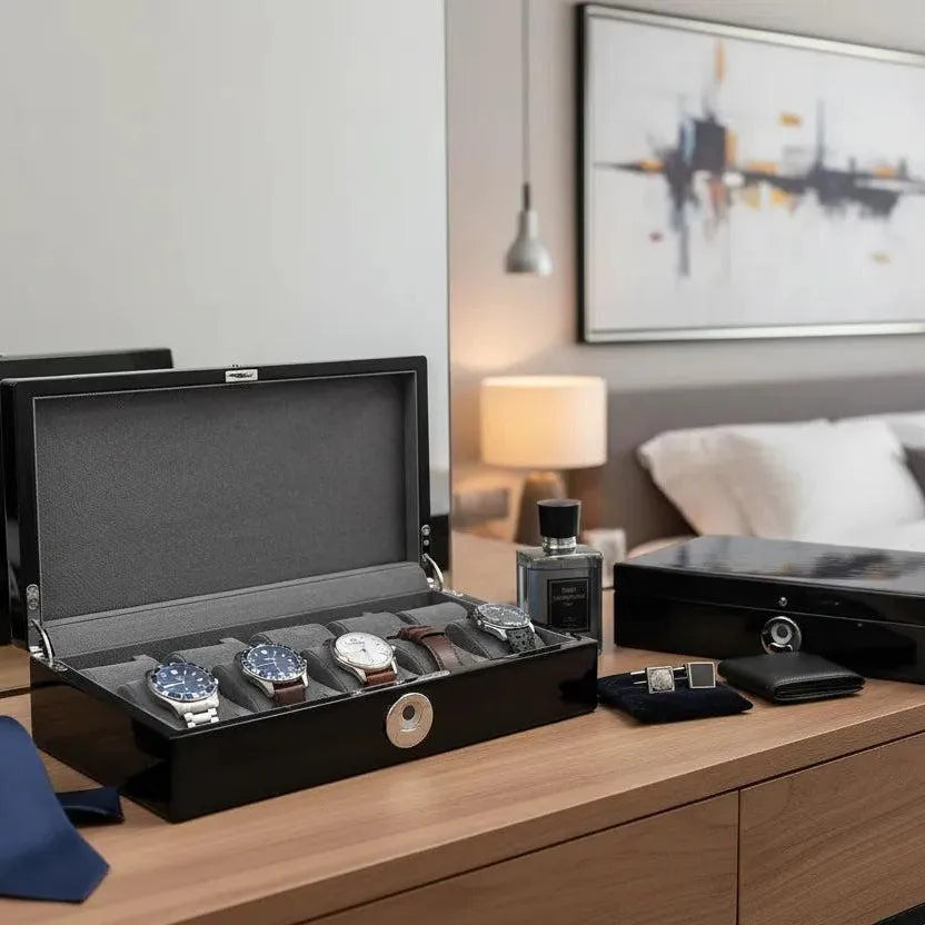 A modern bedroom showcases the Tempus Luxury Watch Winders' Tempus 10 Watch Box in Black Piano Finish with Bio Metric Lock, displaying watches, cologne, a wallet, cufflinks, a blue tie, and another box atop a wooden dresser amid stylish decor.