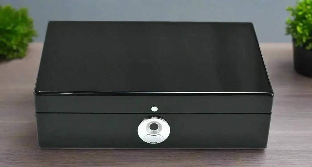 The Tempus 8 Watch Box in Black Piano Finish with Bio Metric Lock by Tempus Luxury Watch Winders sits closed on a wooden surface, flanked by small green potted plants—perfect for luxury watch storage.