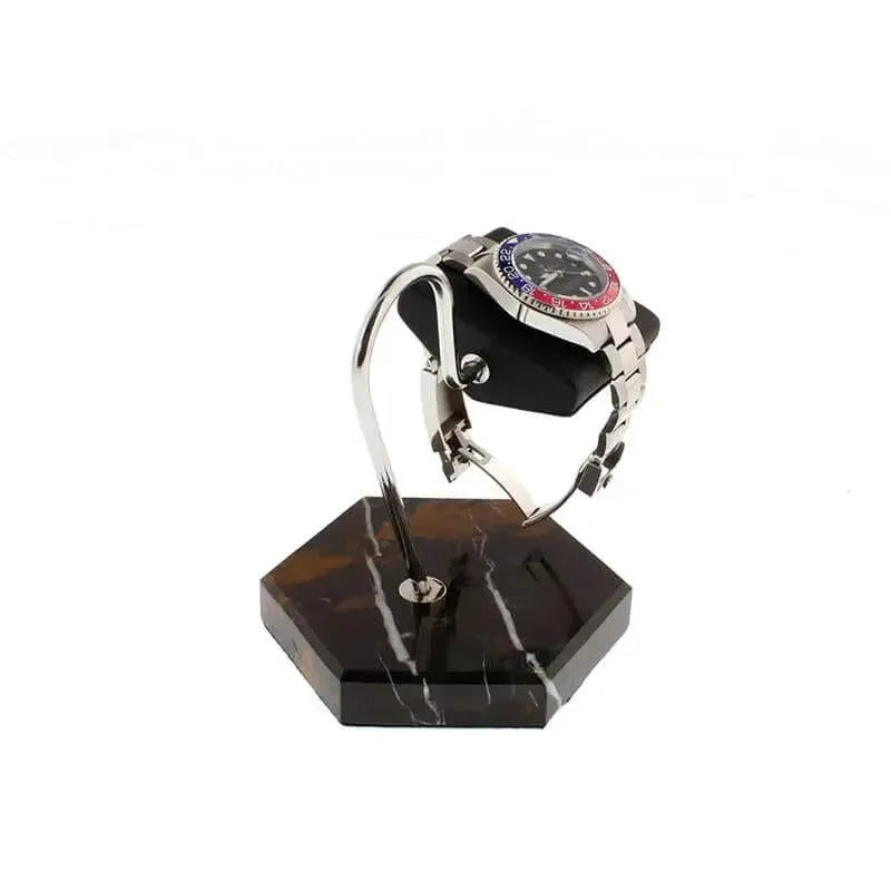 The Tempus Watch Stand by Tempus Luxury Watch Winders features black marble with brown veining and black leather, showcasing a silver wristwatch with a red and blue bezel—an ideal luxury gift against a white background.