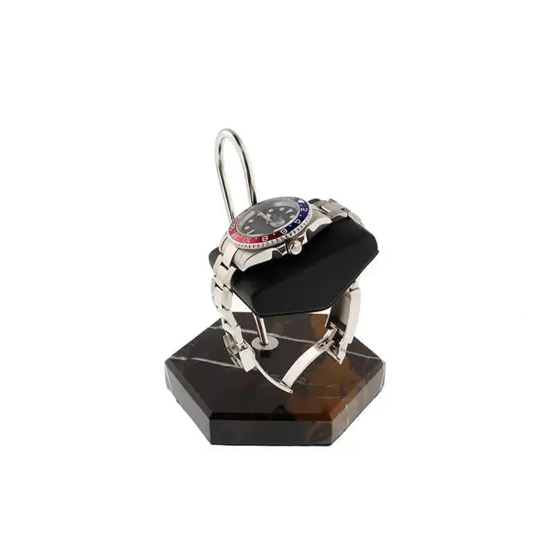A silver wristwatch with a red and blue bezel is displayed on the Tempus Watch Stand in Black Marble Brown Veining with Black Leather by Tempus Luxury Watch Winders—a refined luxury gift against a white backdrop.