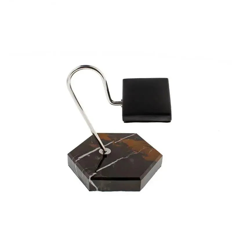The Tempus Watch Stand in Black Marble with brown veining and a black leather pad by Tempus Luxury Watch Winders features a modern hexagonal base and curved metal arm—perfect as a luxury gift, shown on a white background.