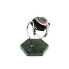 A silver wristwatch with a red and blue bezel is displayed on the Tempus Watch Stand in Green Marble Hexagon Base with Black Leather by Tempus Luxury Watch Winders, set against a white background.