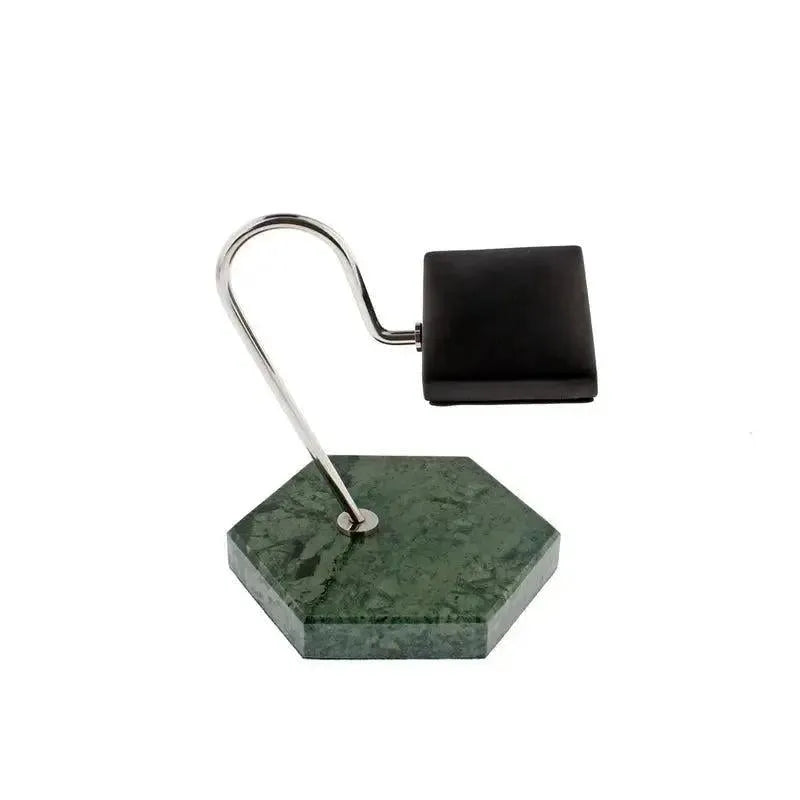 The Tempus Watch Stand by Tempus Luxury Watch Winders features a green marble hexagon base with black leather, complemented by a modern curved silver arm and rectangular black lamp head, echoing the style of a contemporary desk lamp.
