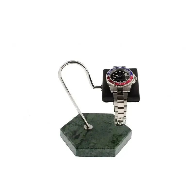 A silver wristwatch with a red and blue bezel is showcased on the Tempus Watch Stand by Tempus Luxury Watch Winders, featuring a green marble hexagonal base with black leather, against a white background.