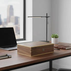 Light walnut wood 10-watch box with natural finish, brass accents, and keyhole on a modern desk.