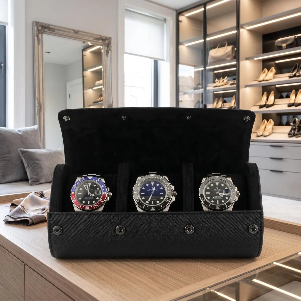 Close-up of black saffiano leather watch roll with textured exterior, fine stitching, dark metal closures in a bright luxury dressing room.