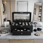 Front view of black oak veneer watch box with drawer and cushioned slots, set in a bright luxurious dressing room environment.