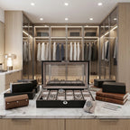 Front view of a black oak veneer 12-watch box with soft suede interior, placed on a polished marble countertop with watches and tools in a lavish dressing room.
