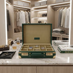 Open green leather 15 watch briefcase with organized watches in a luxurious dressing room setting on a sleek dressing table.