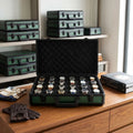 Close-up of luxurious green 24-watch briefcase by Tempus, showing textured finish, lock mechanism, and lift-out tray in modern dressing room.