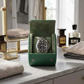 Mini green vegan leather watch roll with suede lining, displayed on a modern dressing table with luxury props in a bright walk-in closet.