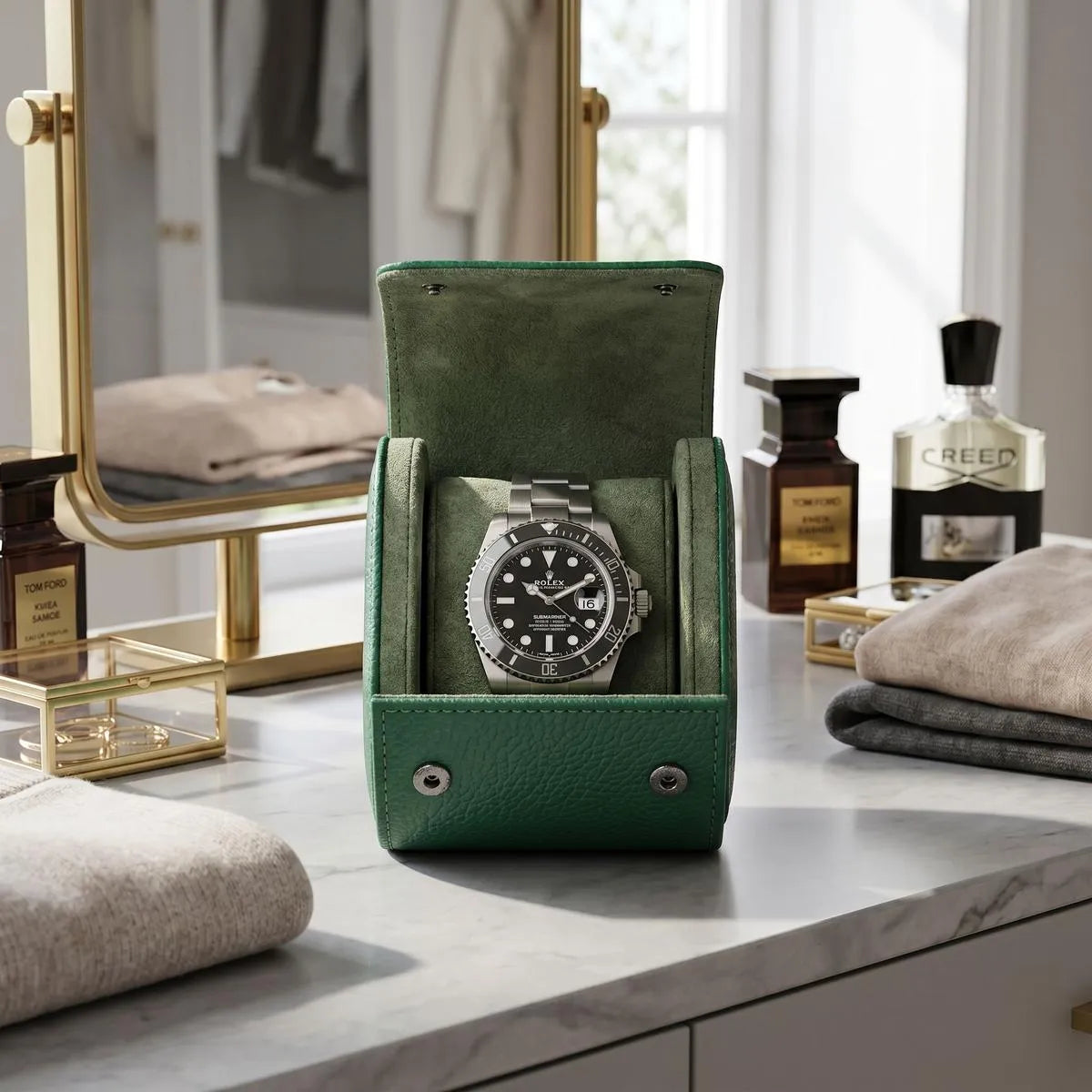 Mini green vegan leather watch roll with suede lining, displayed on a modern dressing table with luxury props in a bright walk-in closet.