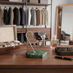 Close-up of a green marble hexagon base watch stand with black leather cushion in a bright, modern dressing room.