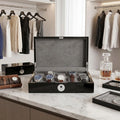 Front view of black piano finish Tempus 10 watch box with biometric lock in a bright luxurious walk-in dressing room, showcasing its sleek design.
