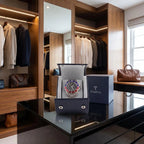 Navy blue Saffiano leather watch roll by Tempus with soft lining, displayed in a luxurious walk-in dressing room with props and ambient lighting.