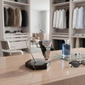Close-up of Tempus watch stand with black marble base, brown veining, and black leather cushion in a bright luxurious walk-in dressing room.