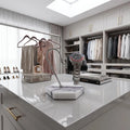White marble watch stand with dark violet veins and black leather cushion, showcased in a modern dressing room setting.